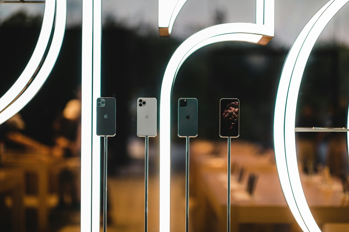 Smartphones displayed vertically on metallic stands in a modern store.